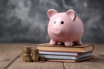 Innovative Funding for Education: Pink Piggy Bank Surrounded by Books and Coins on Wooden Surface