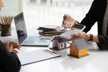 Businessman, real estate agent holding a calculator, presenting a price quote to a client for a house