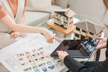 設計図・図面を見ながらマイホームのリフォーム・リノベーションの相談をする女性と建築士