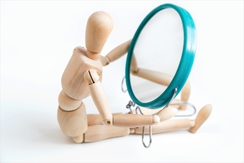 Wooden dummy looks at its reflection in the mirror