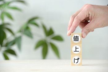 値上げの文字ブロックを積み上げる人の手