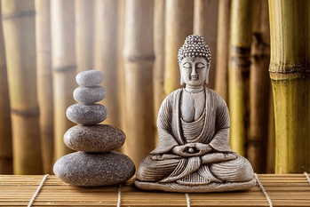 静けさと瞑想のための竹を背景にしたバランスの取れた石の上に置かれた仏像 