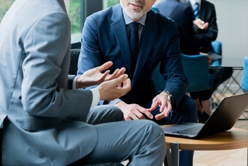 ビルの窓際に座り話す複数のかっこいいビジネスマン