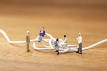 もつれたケーブルと話し合うビジネスマンたち