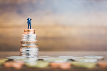 Miniature people businessman standing on money