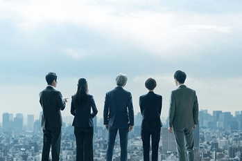 都市を眺めるビジネスパーソンのグループの後ろ姿