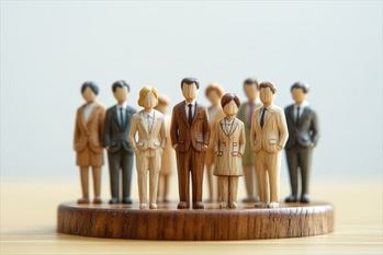木製のミニチュアビジネスマンたちが一列に並ぶ（組織の力・階層構造・リーダーシップ・団結）