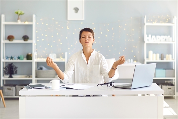 Tired woman sitting in office practicing meditation technique