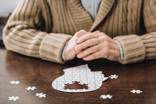 テーブルの上のパズルで遊ぶ年配の男性
