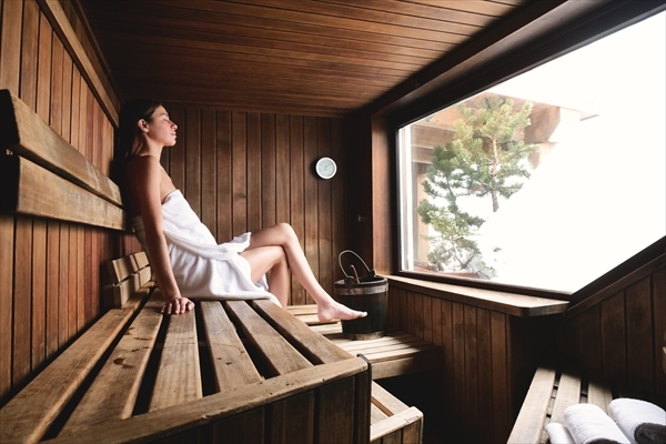 A beautiful woman wearing a white towel takes a sauna