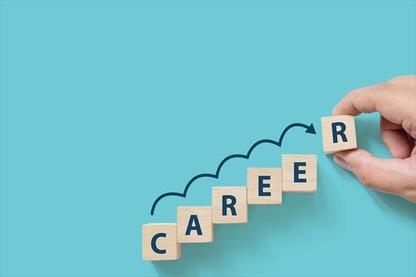 青い背景に「CAREER」という文字とテキスト用のスペースがある木製の立方体ブロックを置く手