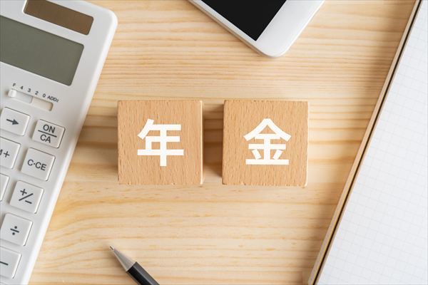 年金と書かれたブロック、電卓、スマホ、ノート