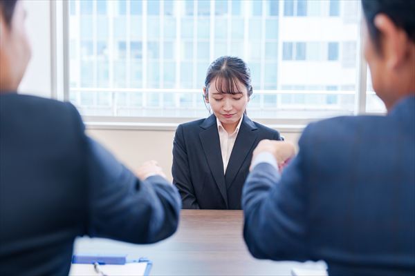 オフィスで上司に詰められて悲しい表情をする女性社員