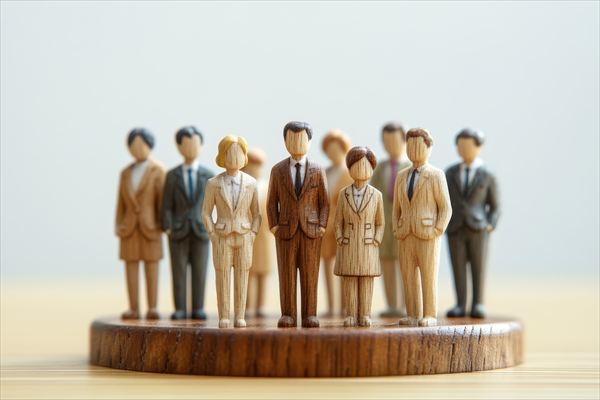 木製のミニチュアビジネスマンたちが一列に並ぶ(組織の力・階層構造・リーダーシップ・団結)